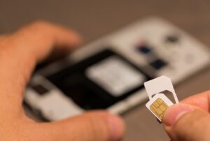 Persona sosteniendo una tarjeta SIM frente a un teléfono móvil