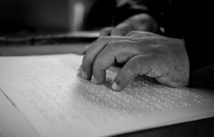 Manos leyendo un texto en braille sobre papel