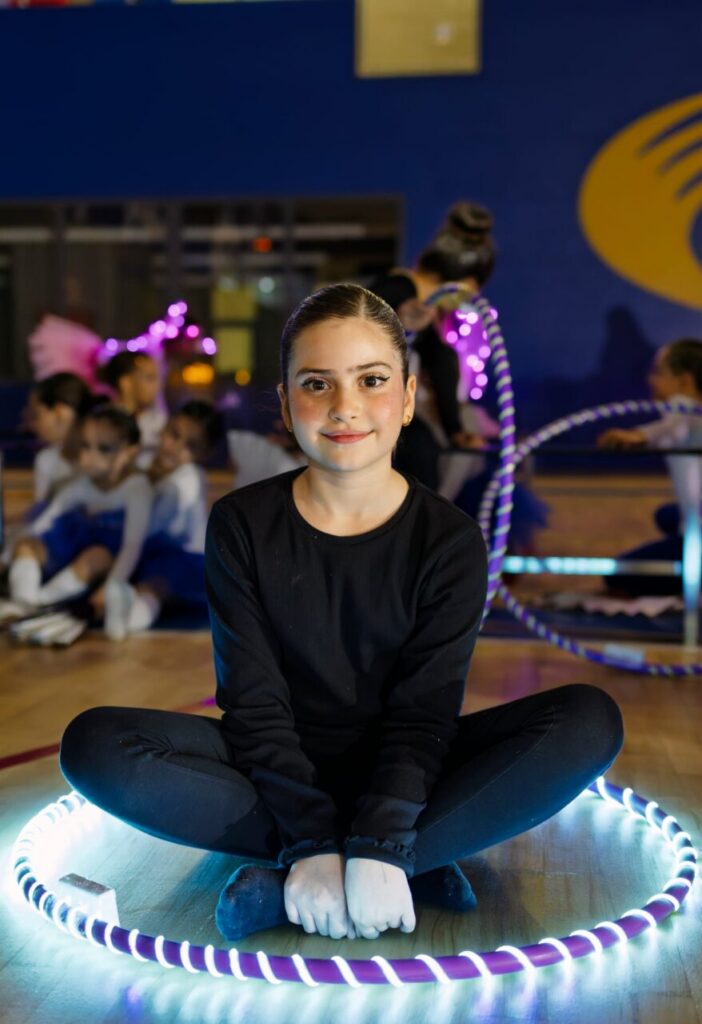 Niña sentada con aro luminoso en festival de gimnasia rítmica