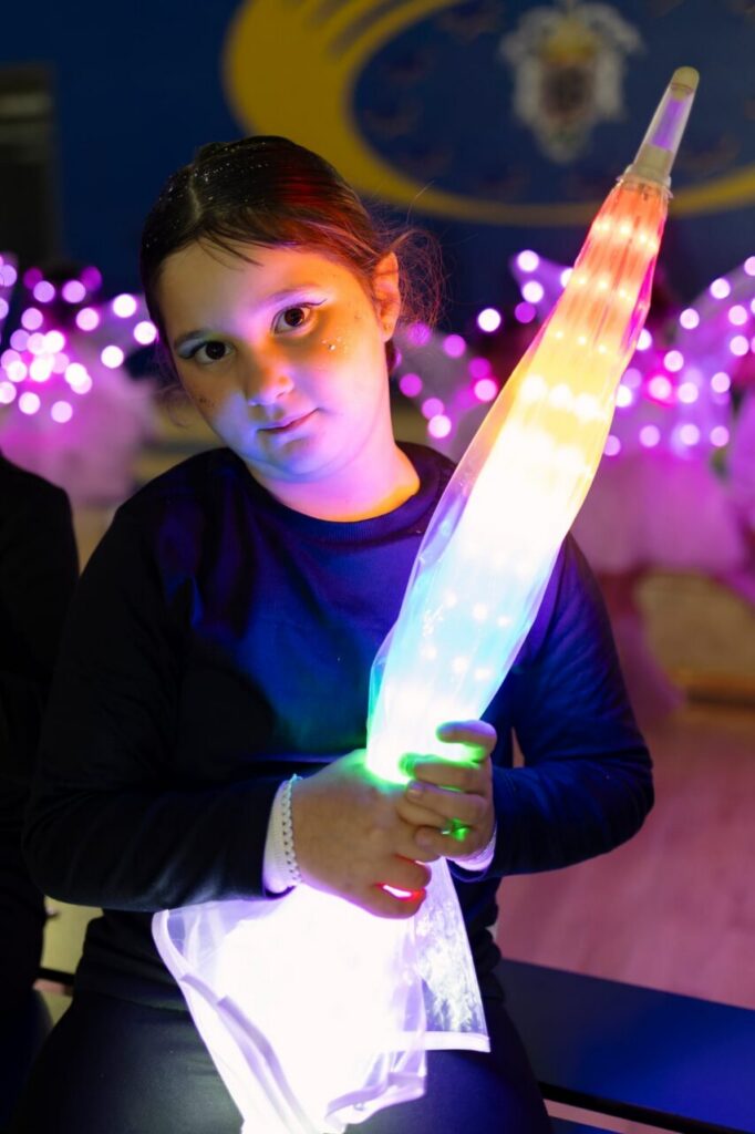 Niña sosteniendo un paraguas iluminado en el festival de Navidad.