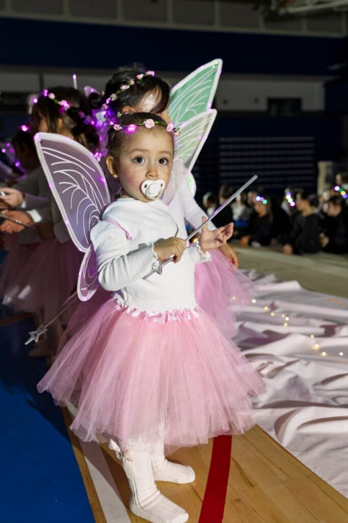 Niña vestida de hada con tutú rosa en festival navideño