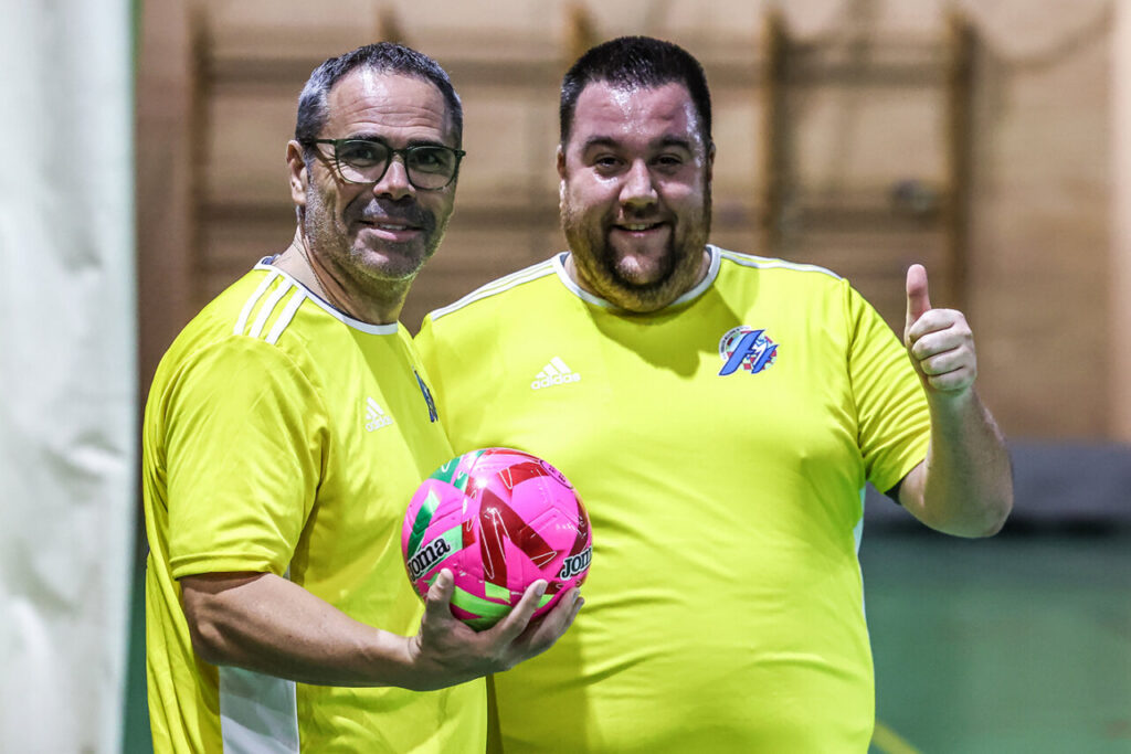 Dos hombres sonrientes en un partido de fútbol navideño