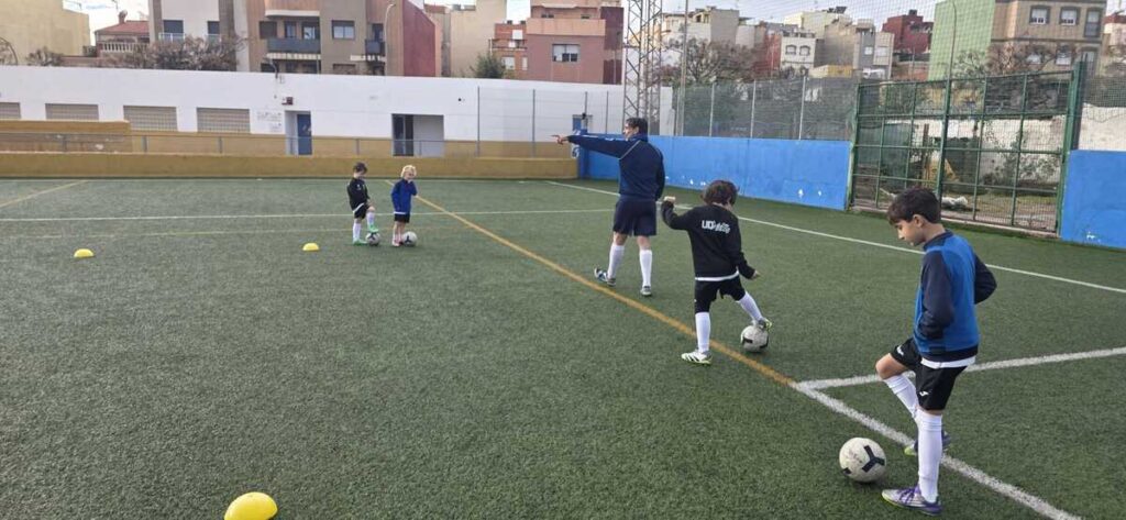 Niños entrenando fútbol en el Campus de Navidad bajo la lluvia