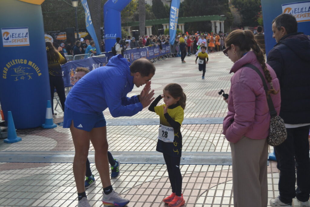 Entrenador animando a niña corredora en la San Silvestre de Melilla