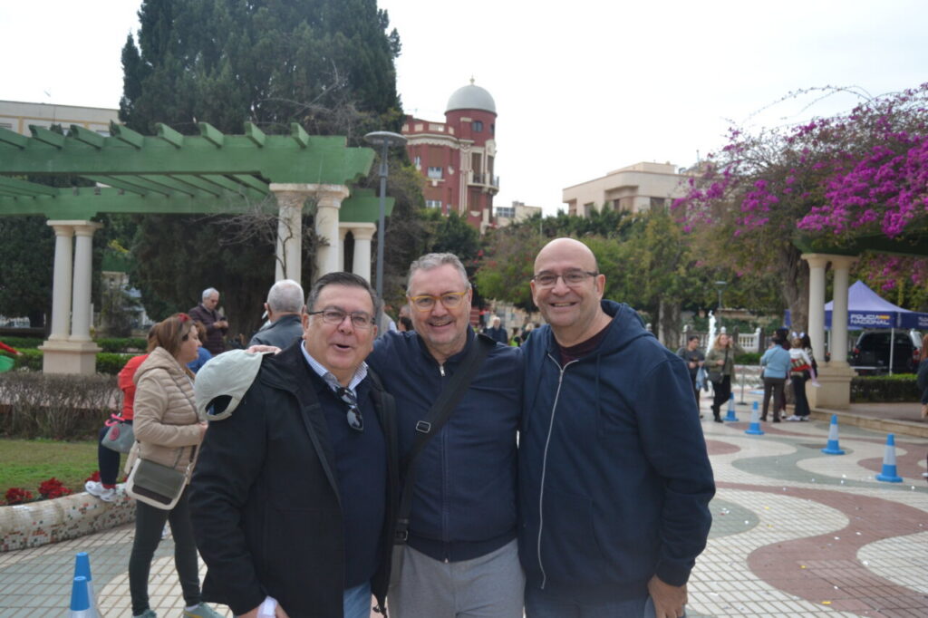 Tres hombres sonrientes en el Parque Hernández durante la San Silvestre de Melilla