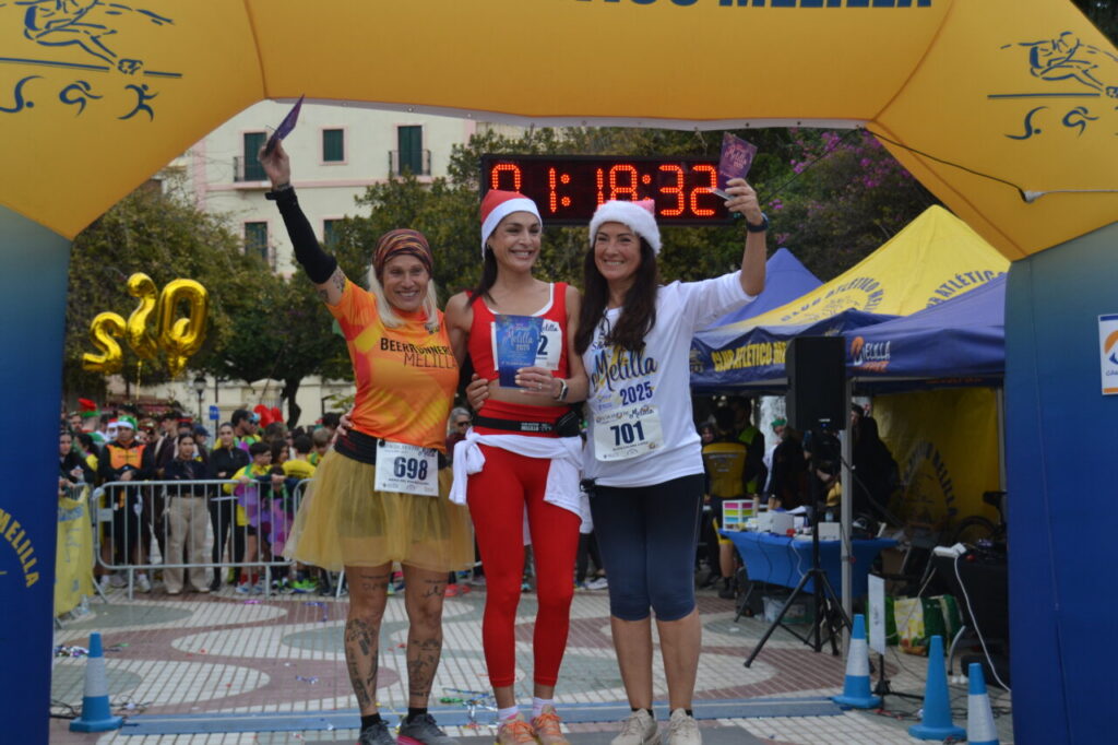 Tres mujeres sonrientes en el podio de la carrera San Silvestre de Melilla