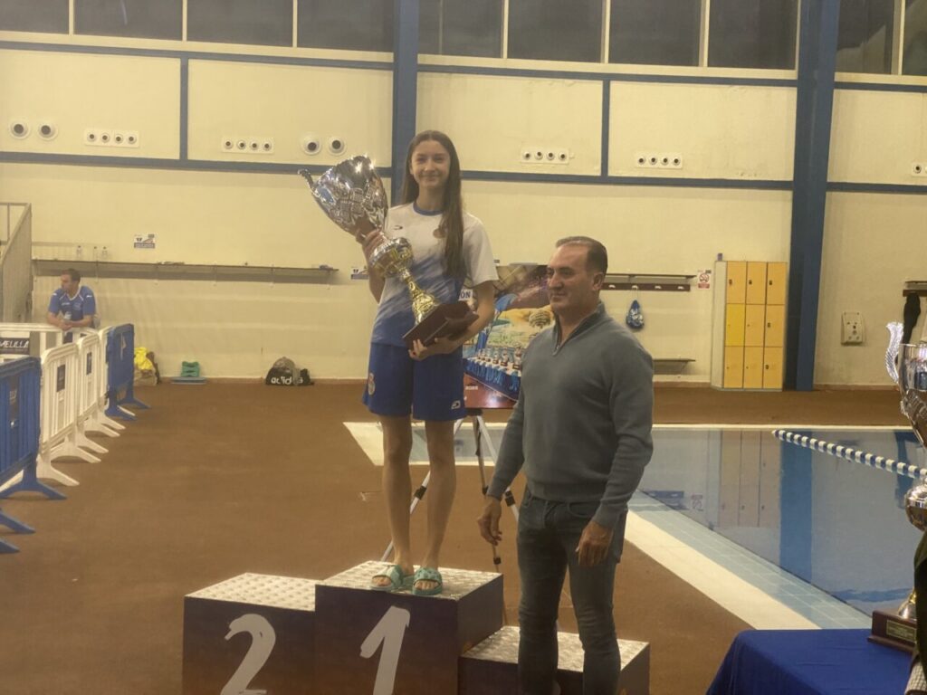 Joven ganadora sosteniendo el trofeo en la piscina de Melilla