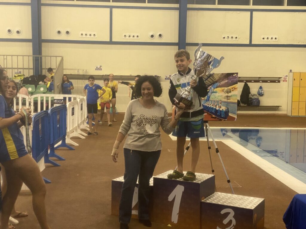 Niño sosteniendo un trofeo en la piscina durante el evento de natación