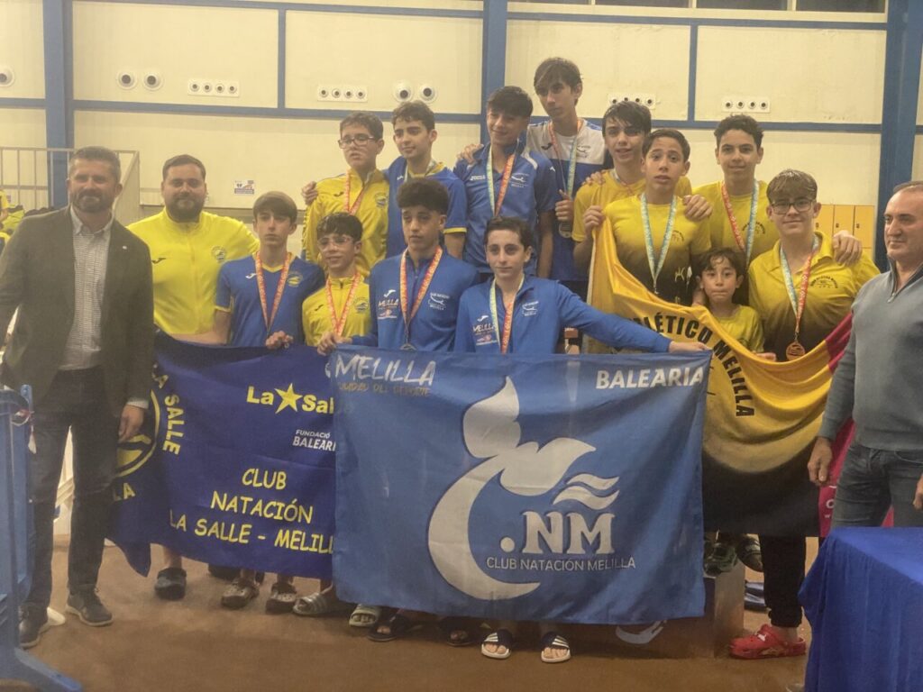 Equipo del Club Natación Melilla con trofeos y banderas en la piscina
