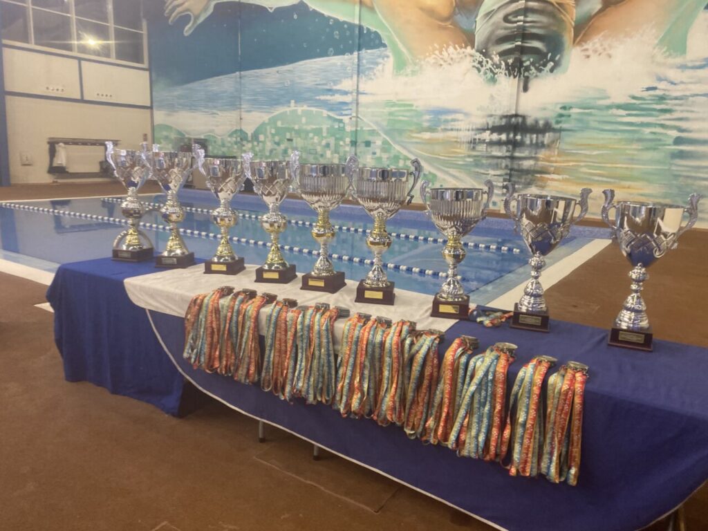 Trofeos y medallas del XIX Trofeo Ciudad de Melilla en la piscina.