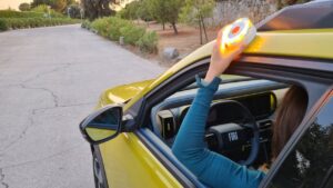 Persona sosteniendo una baliza V16 en un coche amarillo