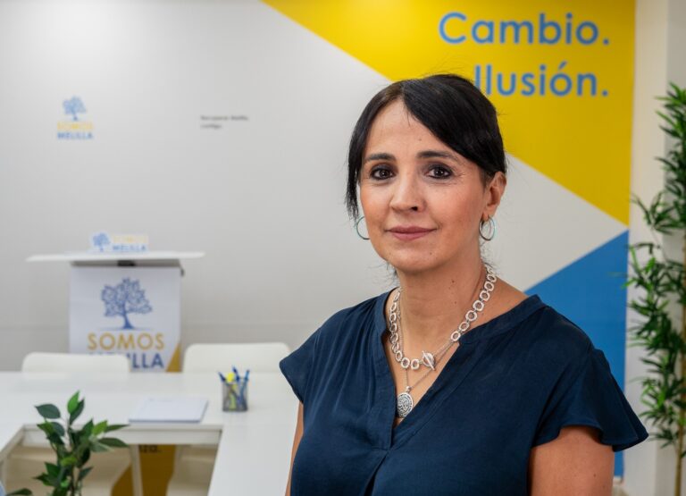 Mujer posando en un entorno de trabajo moderno con decoración colorida.