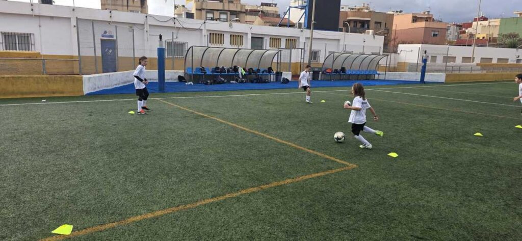 Niños entrenando fútbol en el campus de Navidad bajo la lluvia