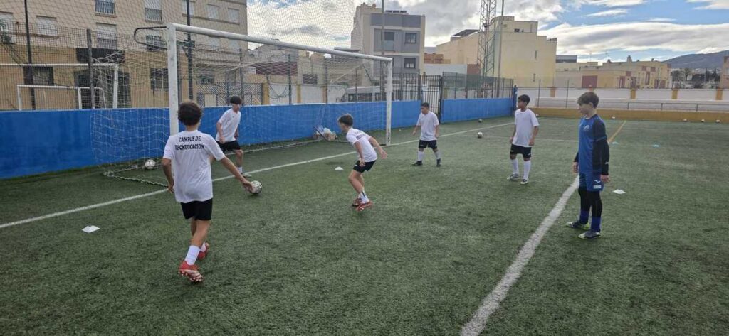 Niños entrenando en el campus de tecnificación de fútbol bajo la lluvia