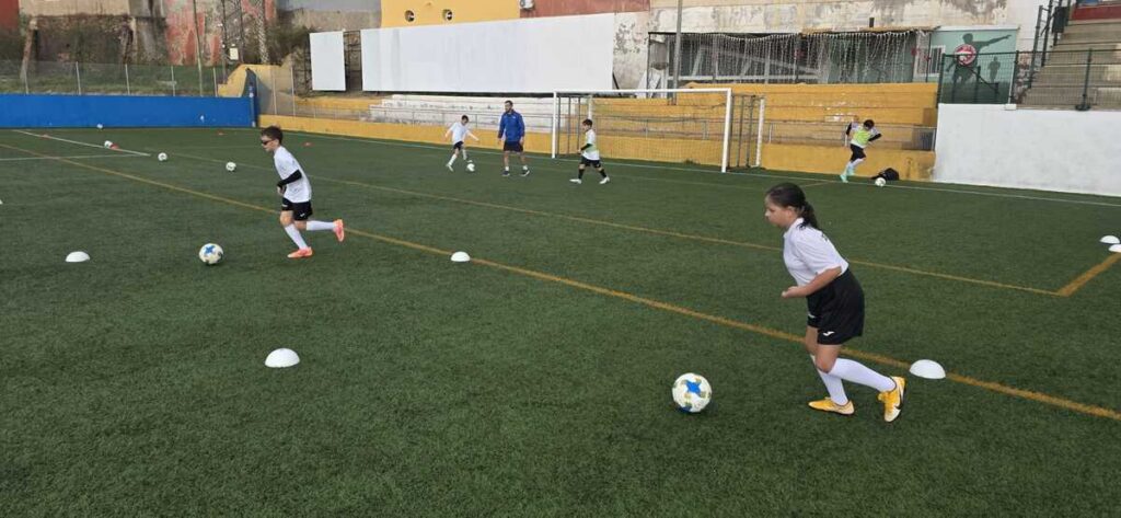 Niños entrenando fútbol en el Campus de Navidad bajo la lluvia