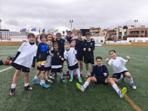 Grupo de niños entrenando en el campo bajo la lluvia