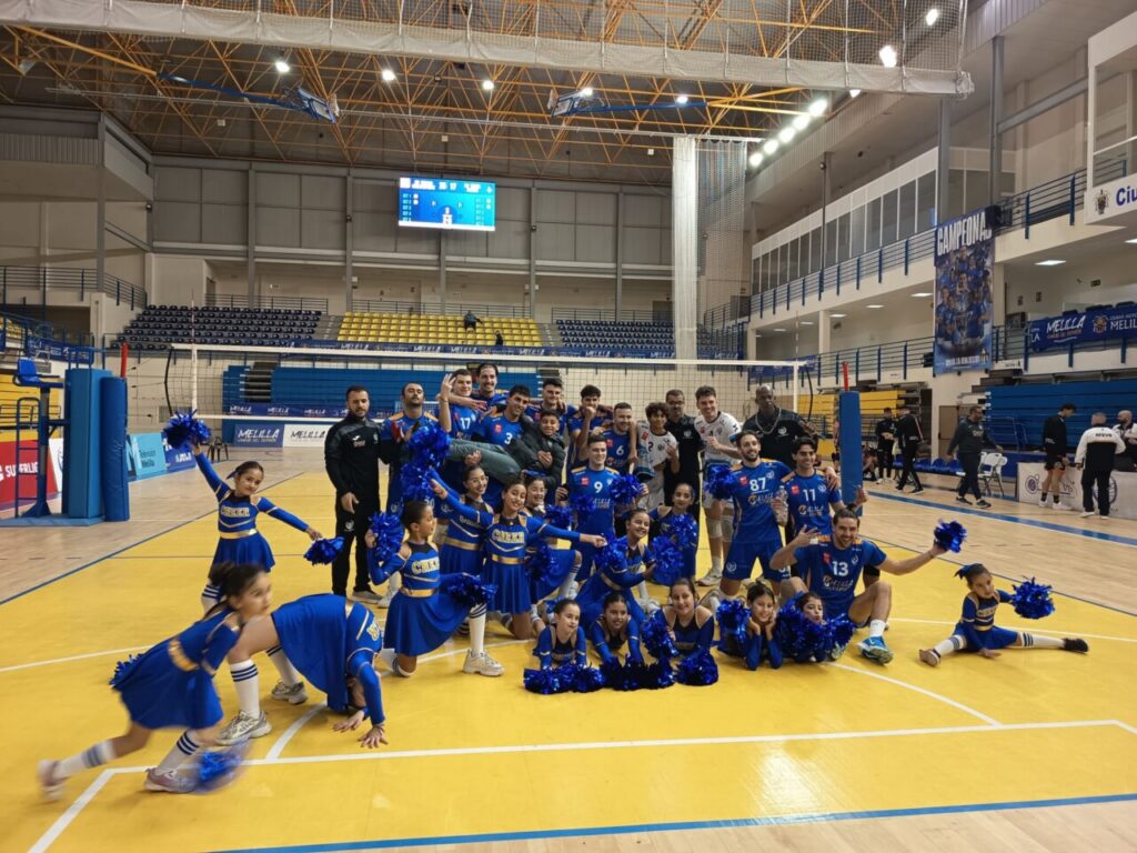 Jugadores y animadoras del Club Voleibol Melilla celebrando una victoria en la cancha.