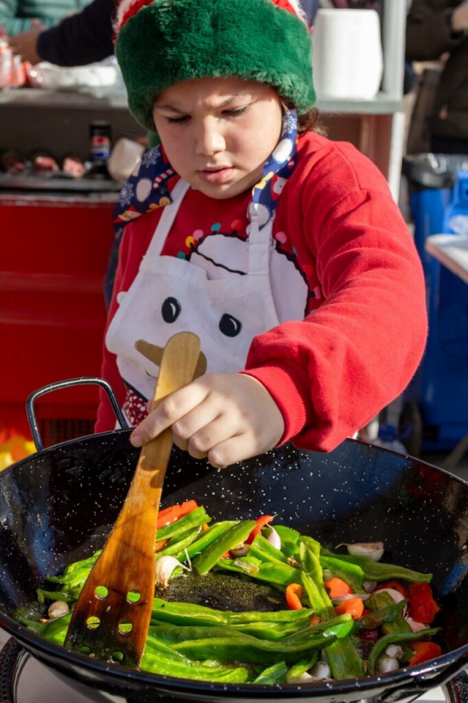 Niño cocinando verduras en un concurso de migas en Melilla