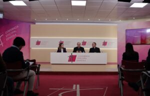 Mesa de conferencia episcopal con ponentes y público asistente