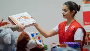 Voluntaria de Cruz Roja entrega un juguete educativo a un niño.