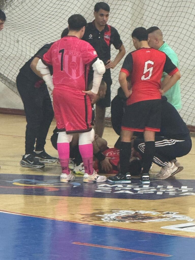 Jugadores de fútbol sala rodeando a un compañero lesionado en el suelo