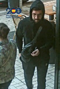 Hombre detenido en un cajero automático con bandolera y ropa oscura.