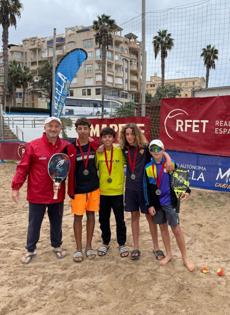 Cuatro jóvenes jugadores de tenis playa con medallas en la playa de San Lorenzo.