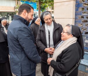 Un hombre conversando con hermanas religiosas en la calle.