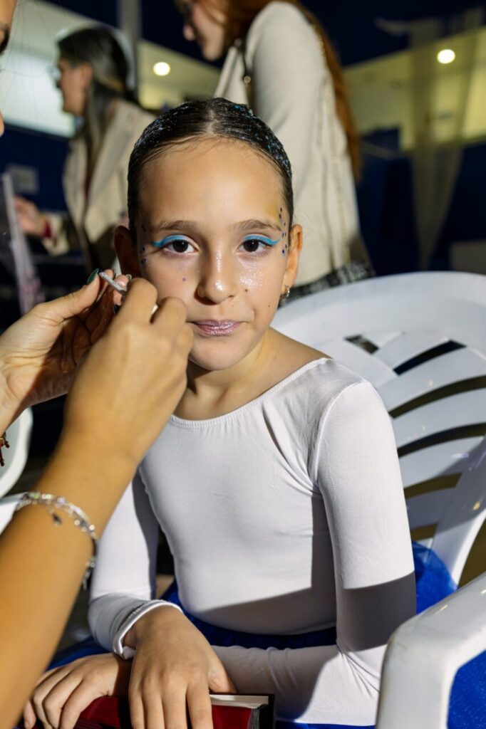 Niña con maquillaje y vestuario de gimnasia rítmica en festival navideño