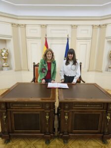 Dos mujeres firmando un acuerdo en un entorno oficial