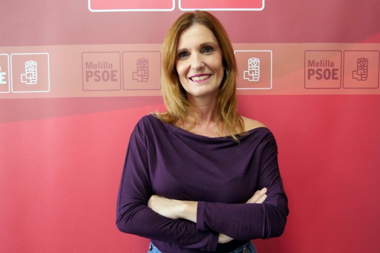 Mujer sonriendo con brazos cruzados frente a un fondo rojo