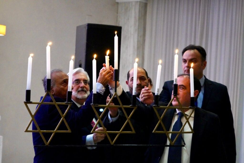 Ceremonia de Janucá con hombres encendiendo velas en un candelabro