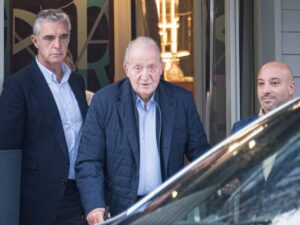 Juan Carlos I saliendo de un edificio con dos acompañantes