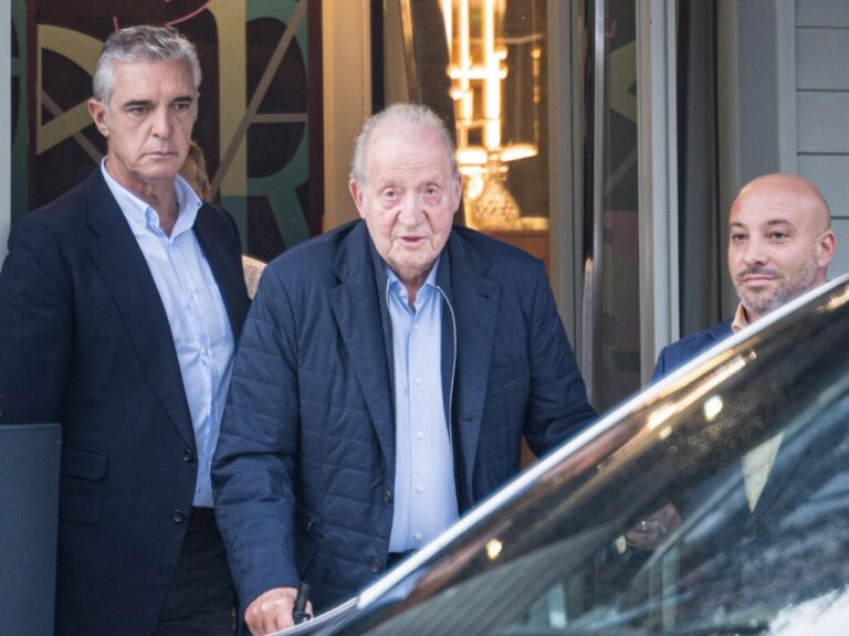 Juan Carlos I saliendo de un edificio con dos acompañantes