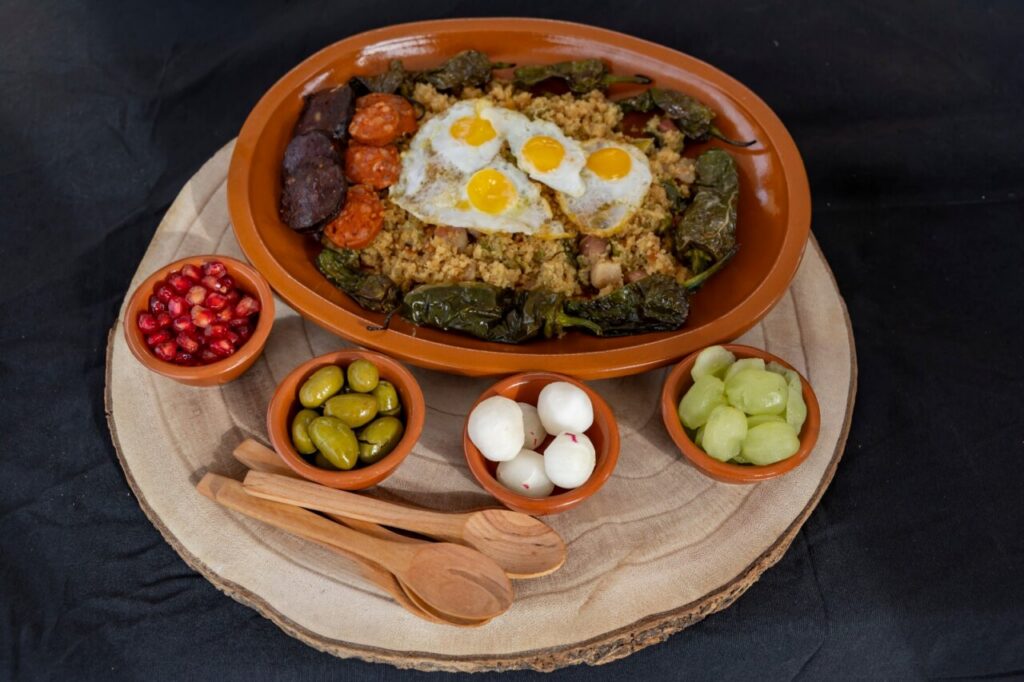 Plato de migas con huevos y embutidos en una mesa