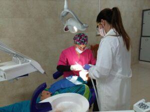 Dos odontólogos realizando un tratamiento dental a un paciente en consulta
