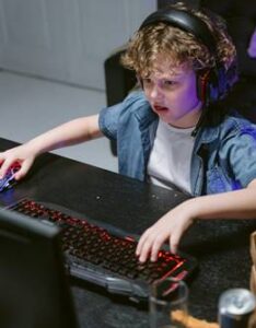 Niño jugando en computadora con auriculares en un entorno de juego