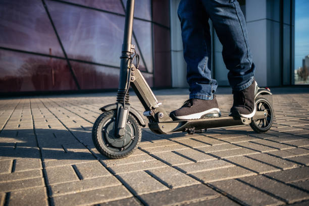 Persona usando un patinete eléctrico en una acera moderna