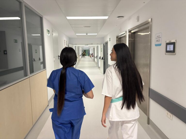Dos profesionales de la salud caminando por un pasillo de hospital.