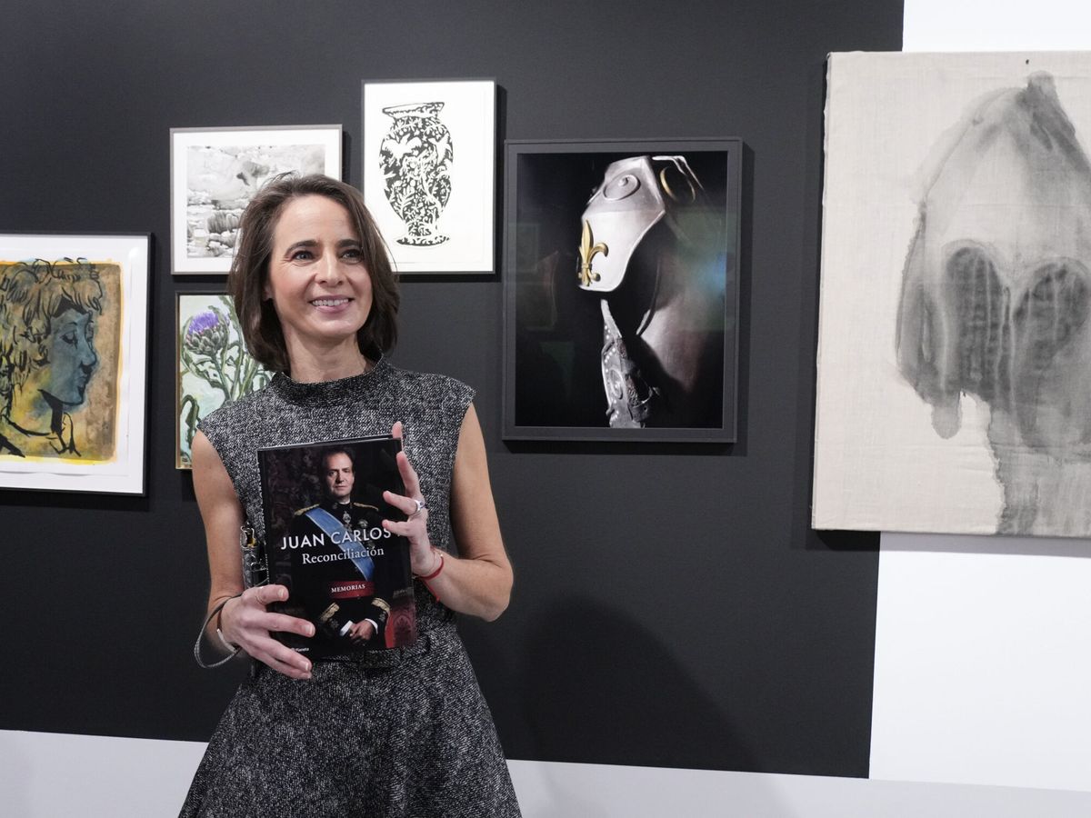 Mujer sosteniendo el libro 'Reconciliación' de Juan Carlos I en una galería de arte.