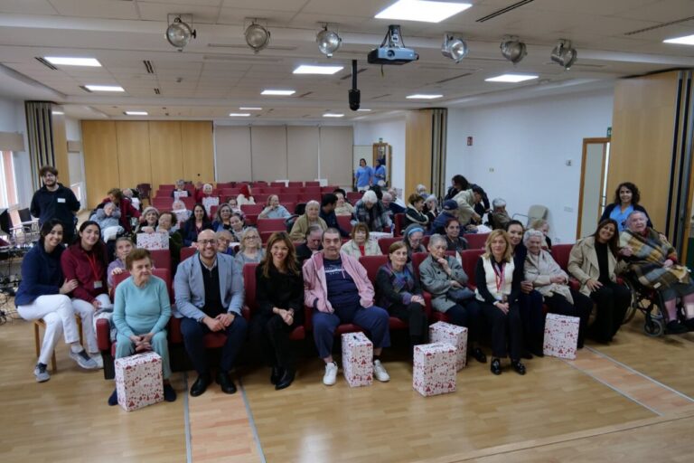 Grupo de personas mayores recibiendo cestas navideñas en un centro.