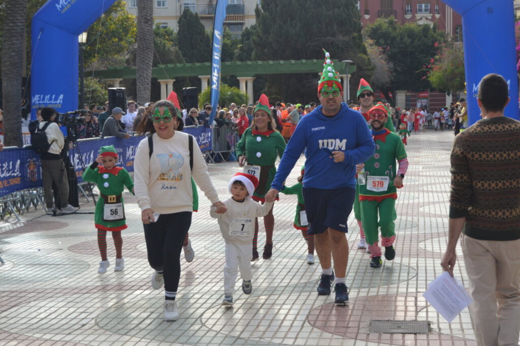 Familias corriendo en la San Silvestre de Melilla con disfraces navideños