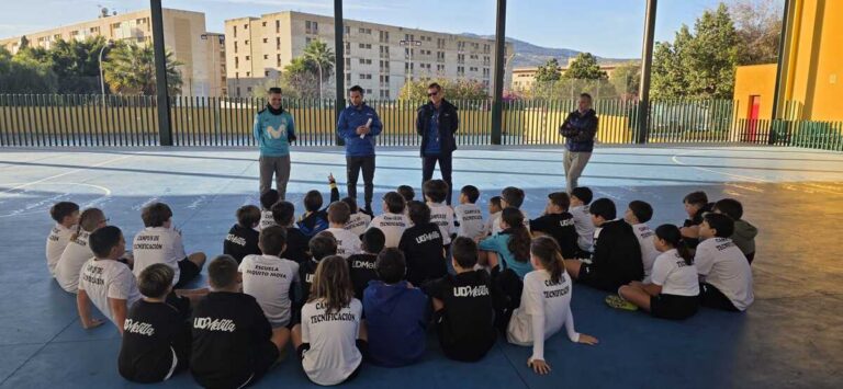 Niños sentados escuchando a entrenadores en el campus de Navidad