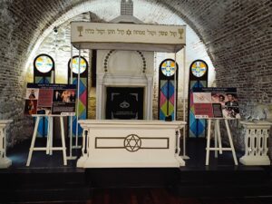 Interior de una sinagoga con vitrales y paneles informativos