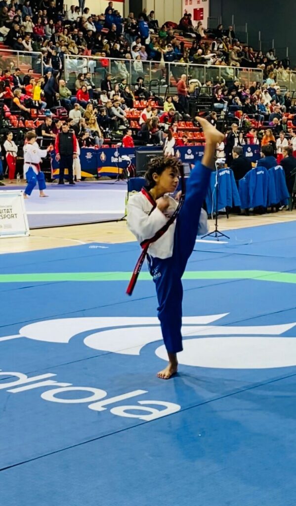 Joven deportista de taekwondo realizando una patada en competición