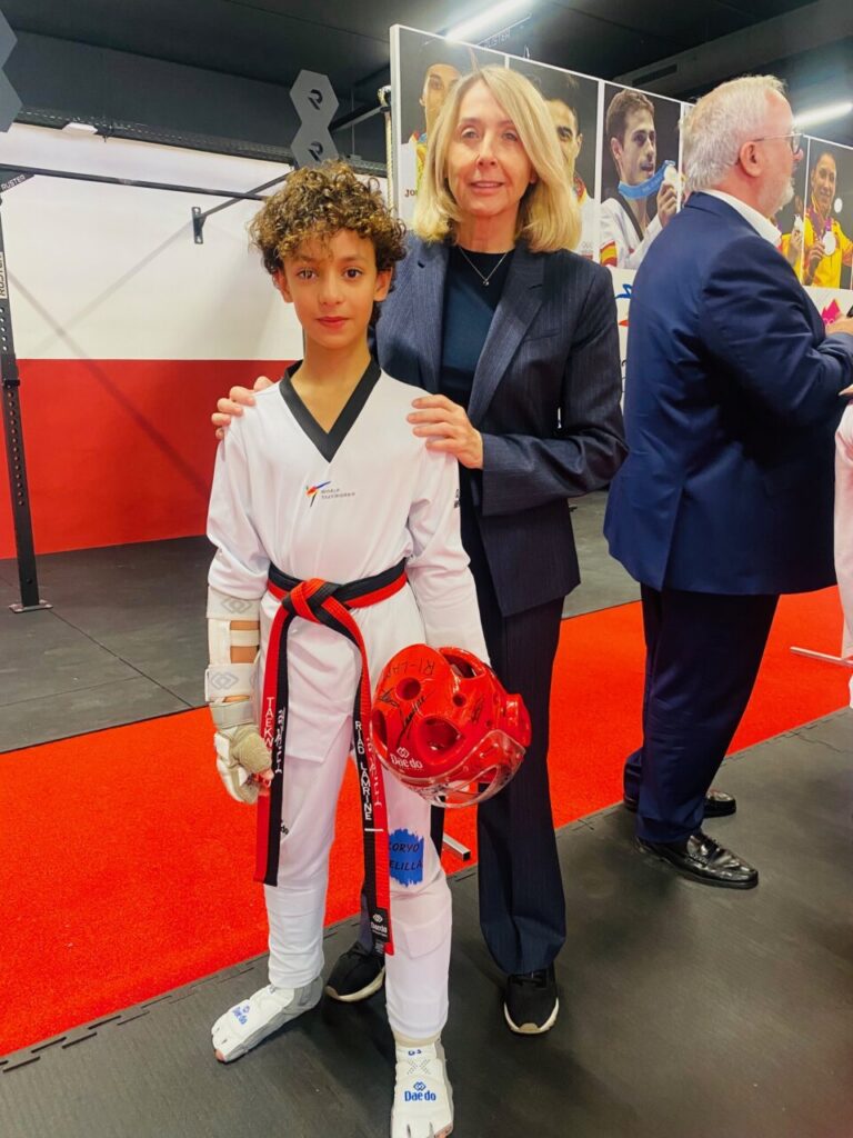 Joven taekwondista con medalla y adulto en evento deportivo