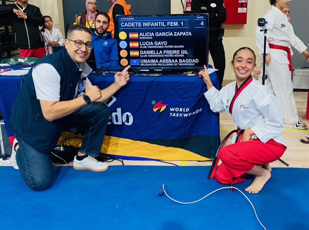 Umaima Assbaa Bagdad sonríe junto a un entrenador en el Campeonato de España de Taekwondo.