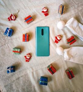 Teléfono móvil rodeado de decoraciones navideñas y regalos pequeños