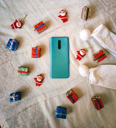 Teléfono móvil rodeado de decoraciones navideñas y regalos pequeños