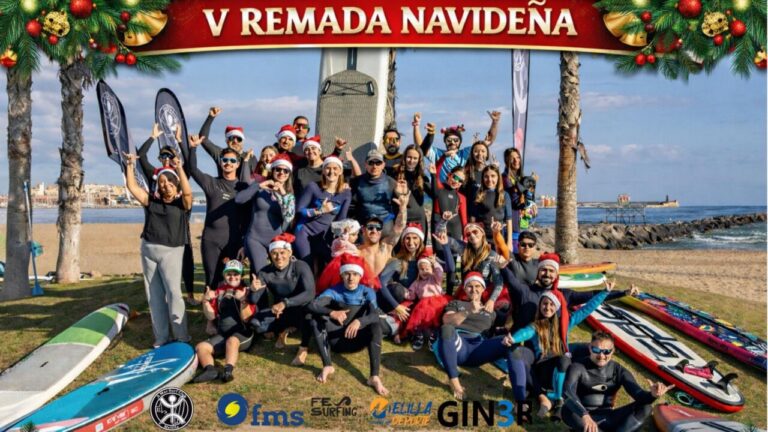 Grupo de personas en la playa celebrando la V Remada Navideña con trajes de surf y gorros navideños.